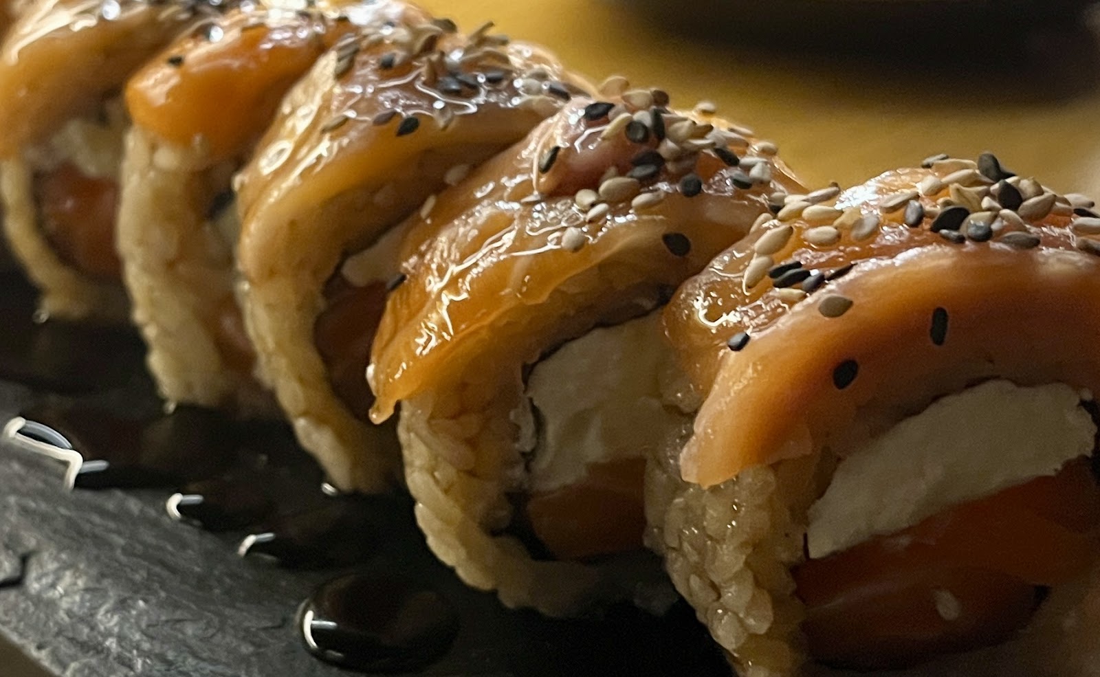 Primer plano de un roll de salmón flameado con sésamo
